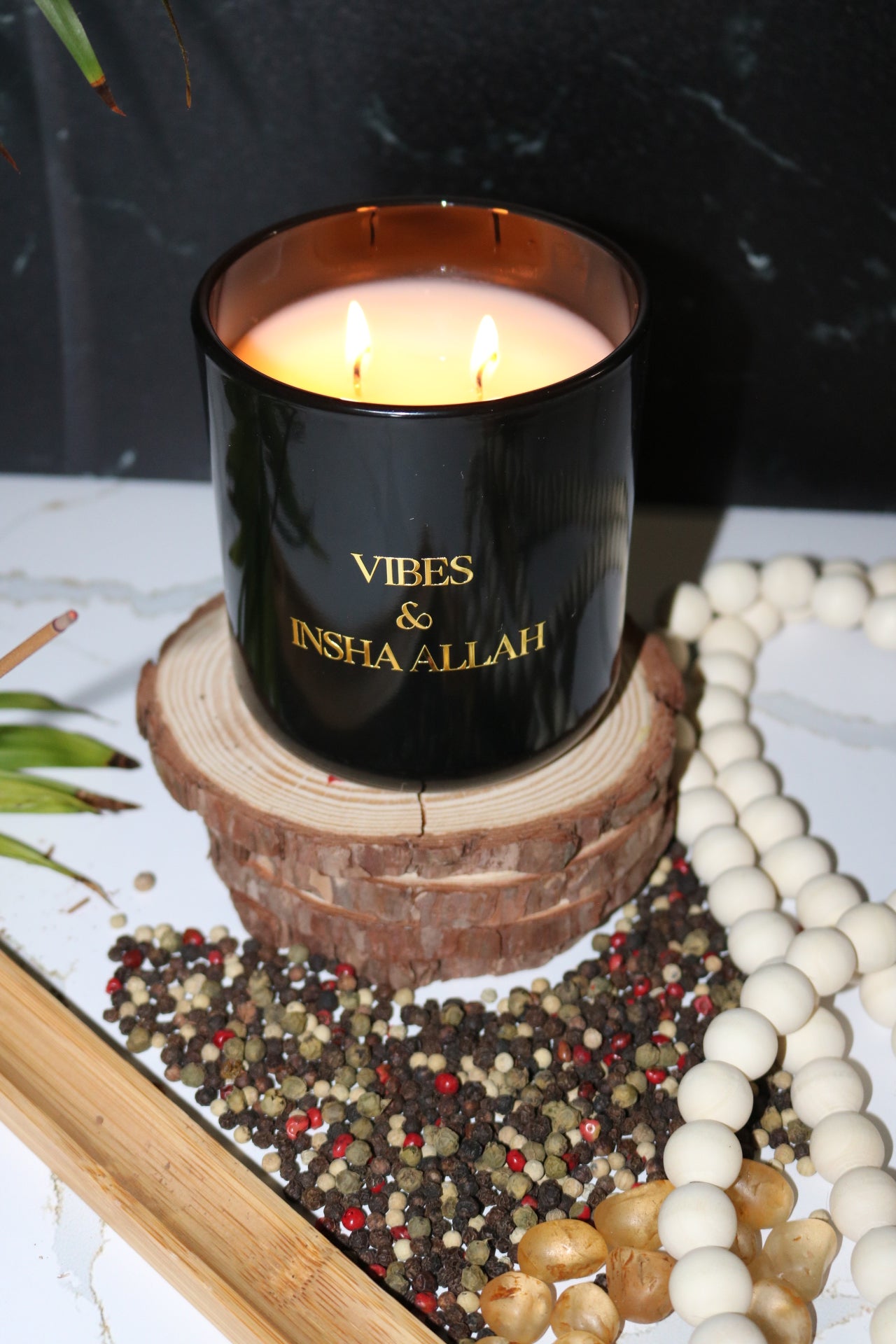 Hand poured black  candle glass jar with a gold metal logo label, featuring multiple organic wicks, burning with a warm glow. The candle is made with natural coconut and soy wax and non toxic fragrance oils. Decorative candle for aesthetic appeal