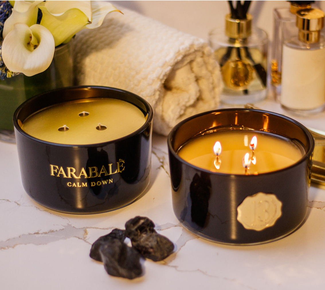 Hand poured black candle glass bowl with a gold metal logo label, featuring multiple organic wicks, burning with a warm glow. The candle is made with natural coconut and soy wax and non toxic fragrance oils. Decorative candle for aesthetic appeal