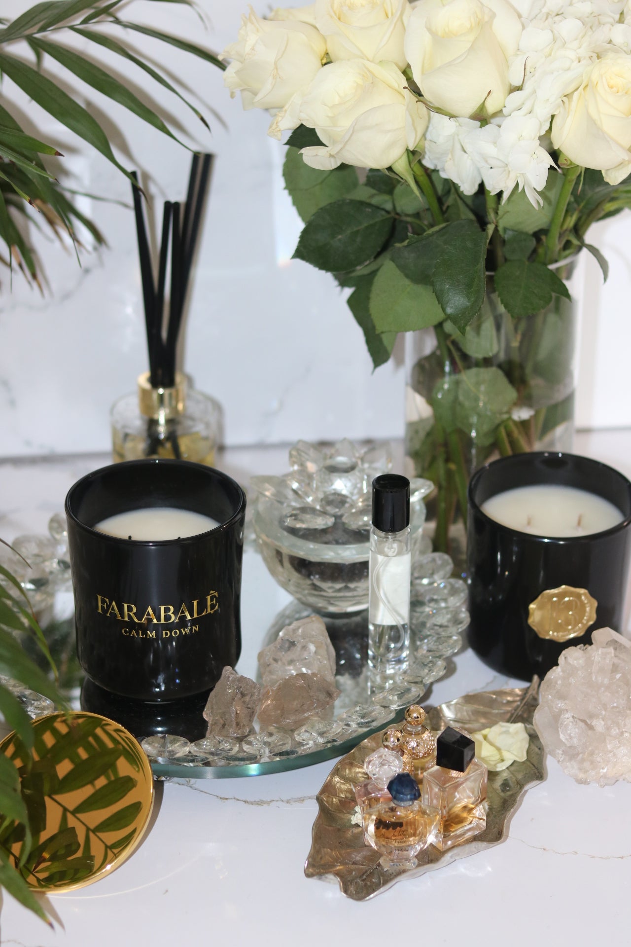 A black candle glass jar with a gold metal logo label, featuring multiple organic wicks, burning with a warm glow. The candle is made with natural coconut and soy wax and non toxic fragrance oils. Decorative candle for aesthetic appeal