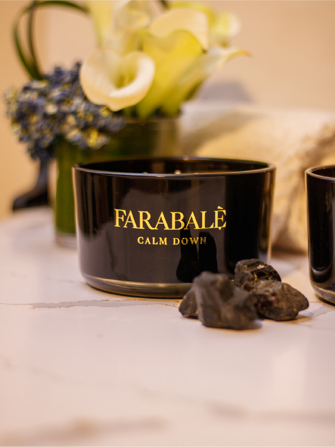 Hand poured black  candle glass bowl with a gold metal logo label, featuring multiple organic wicks, burning with a warm glow. The candle is made with natural coconut and soy wax and non toxic fragrance oils. Decorative candle for aesthetic appeal