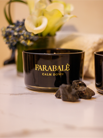 Hand poured black  candle glass bowl with a gold metal logo label, featuring multiple organic wicks, burning with a warm glow. The candle is made with natural coconut and soy wax and non toxic fragrance oils. Decorative candle for aesthetic appeal