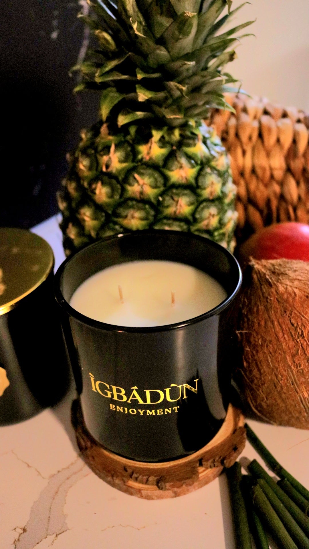 Hand poured black candle container with a gold metal logo label, featuring multiple organic wicks, burning with a warm glow. The candle is made with natural coconut and soy wax and non toxic fragrance oils. Decorative candle for aesthetic appeal