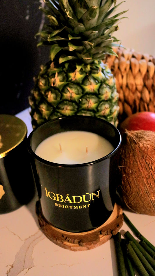 Hand poured black candle container with a gold metal logo label, featuring multiple organic wicks, burning with a warm glow. The candle is made with natural coconut and soy wax and non toxic fragrance oils. Decorative candle for aesthetic appeal