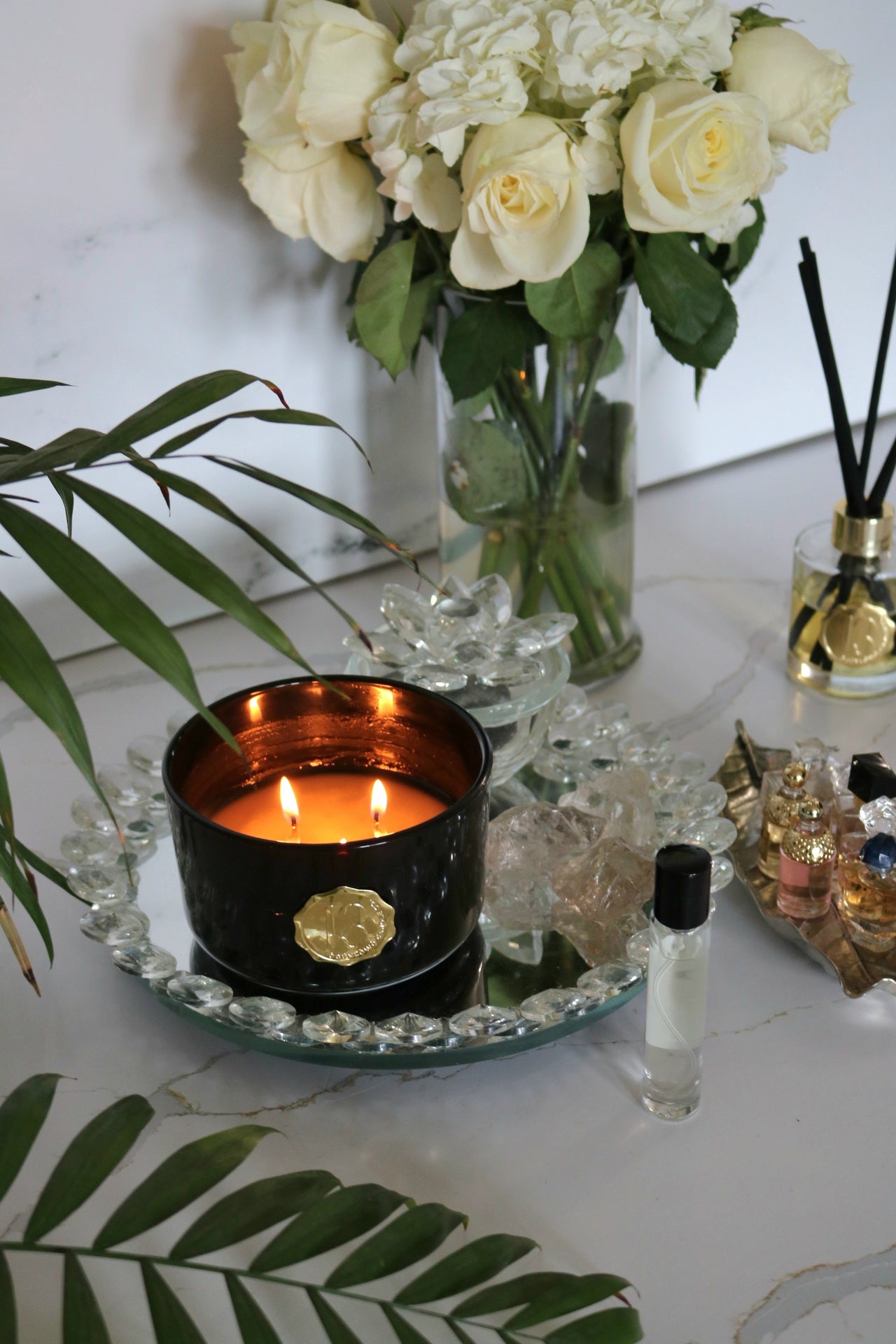 Hand poured black candle glass bowl with a gold metal logo label, featuring multiple organic wicks, burning with a warm glow. The candle is made with natural coconut and soy wax and non toxic fragrance oils. Decorative candle for aesthetic appeal