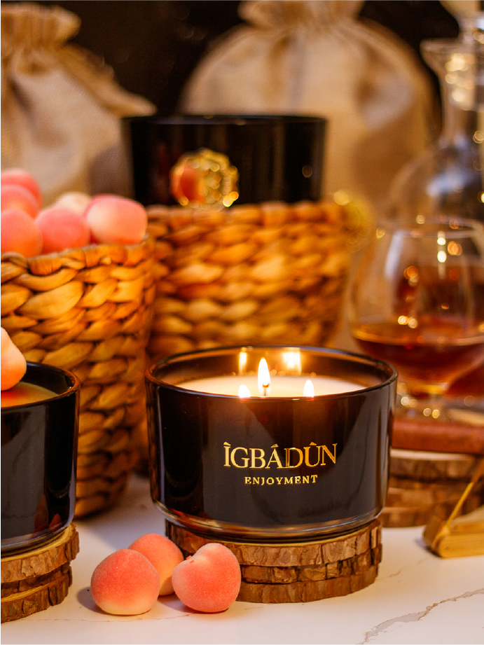 Hand poured black candle glass bowl with a gold metal logo label, featuring multiple organic wicks, burning with a warm glow. The candle is made with natural coconut and soy wax and non toxic fragrance oils. Decorative candle for aesthetic appeal