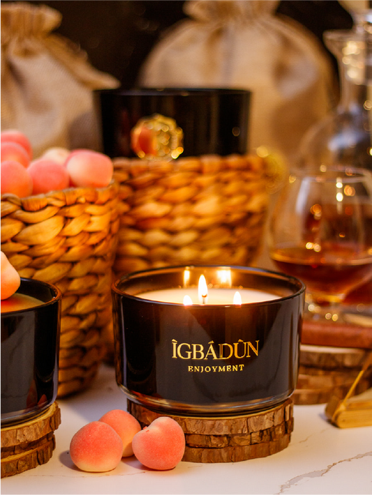 Hand poured black candle glass bowl with a gold metal logo label, featuring multiple organic wicks, burning with a warm glow. The candle is made with natural coconut and soy wax and non toxic fragrance oils. Decorative candle for aesthetic appeal