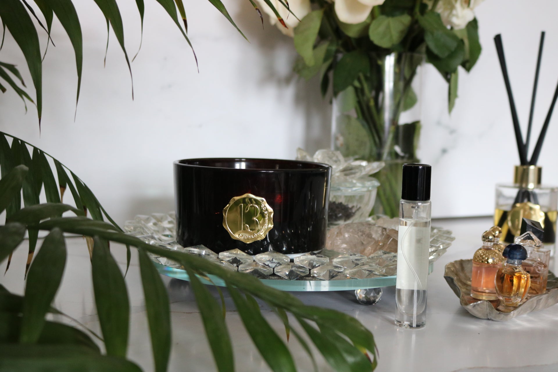 Hand poured black  candle glassbowl with a gold metal logo label, featuring multiple organic wicks, burning with a warm glow. The candle is made with natural coconut and soy wax and non toxic fragrance oils. Decorative candle for aesthetic appeal